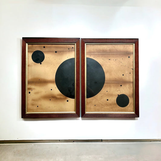 Two framed abstract artworks with black circles on a white wall.