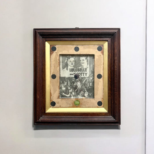 Framed picture with gold interior and black border on a white wall