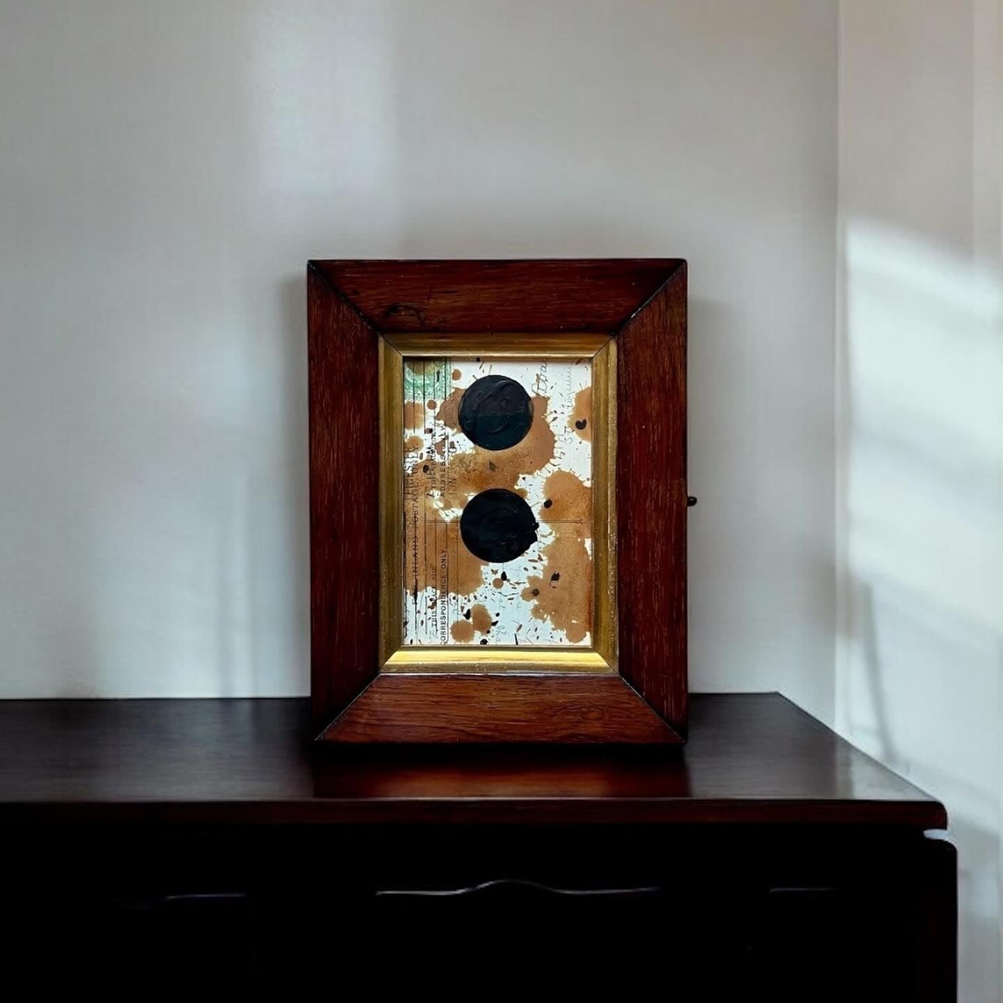 Decorative item with a wooden frame on a dark surface against a white wall