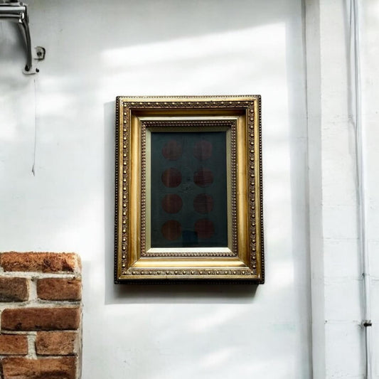 Gold-framed artwork on a white wall next to a brick column.