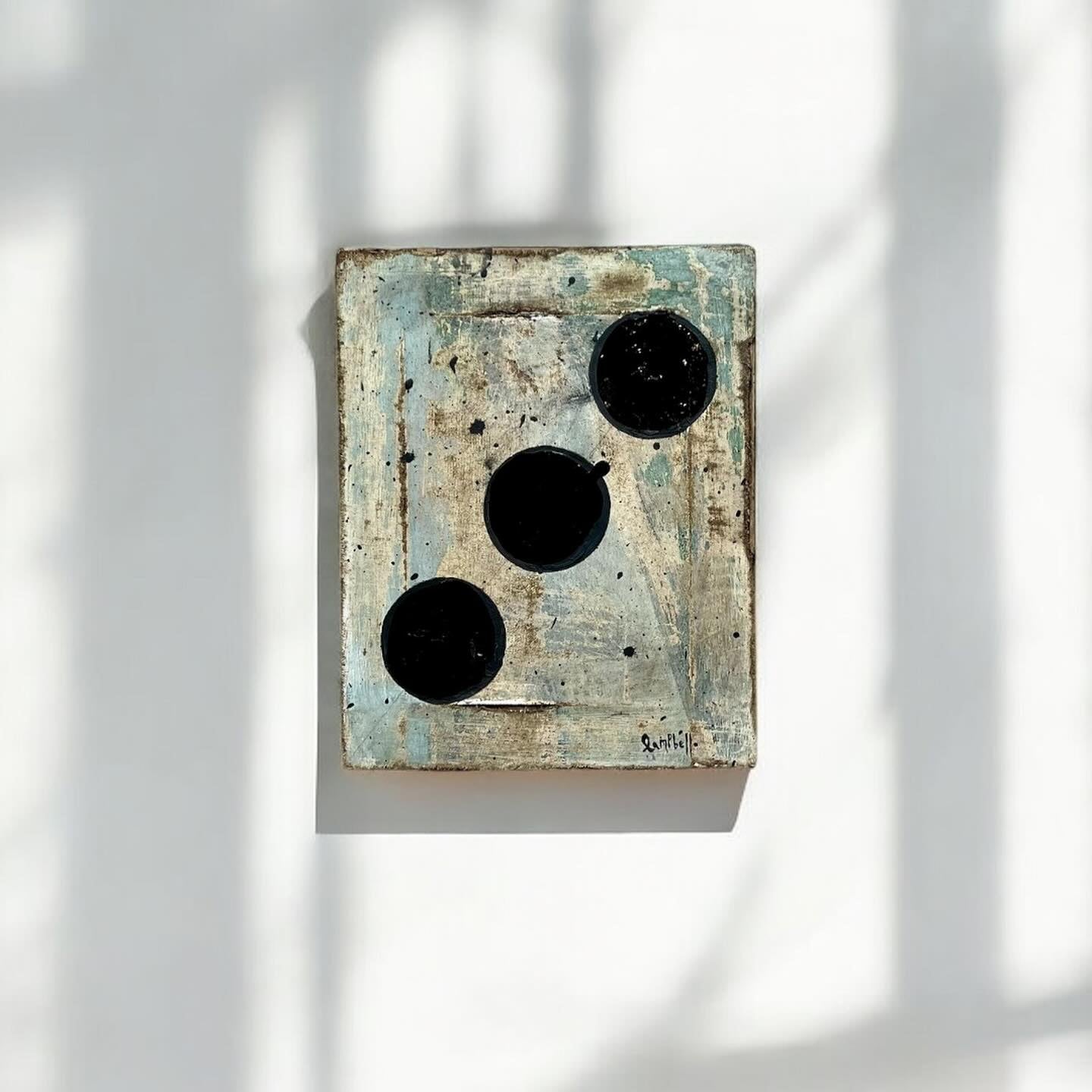 Abstract wall art with black and white elements on a textured surface