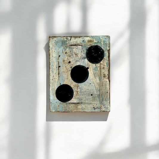 Abstract wall art with black and white elements on a textured surface