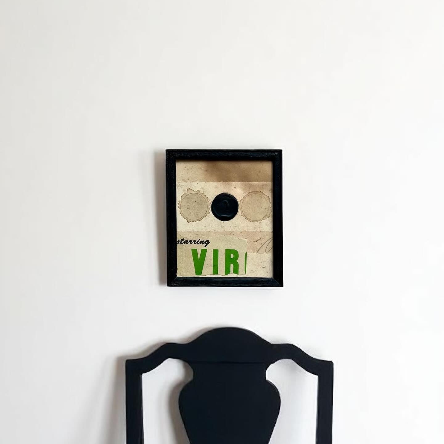 Framed artwork with text and a circular design on a white wall.
