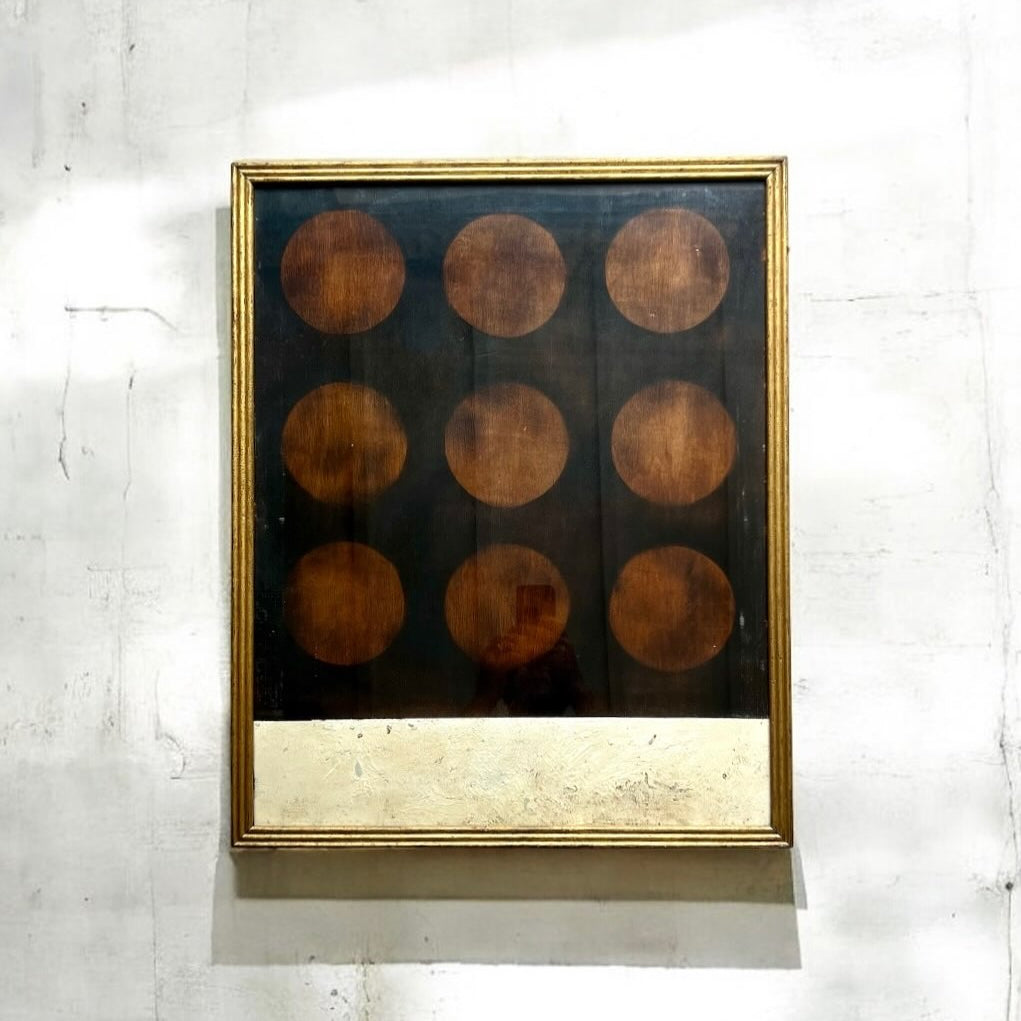 Framed artwork with circular patterns on a textured wall
