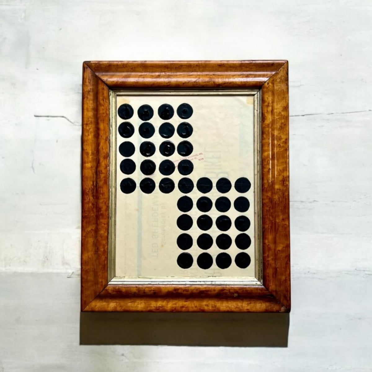 Framed artwork with black circular patterns on a light background