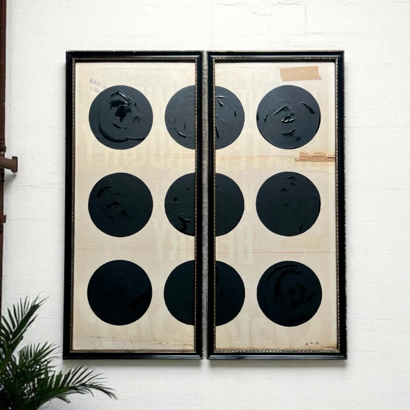 Two framed pieces of art with black circular patterns on a white wall.